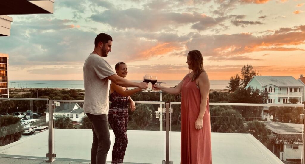 three people toasting with wine overlooking sarasota view  from balcony