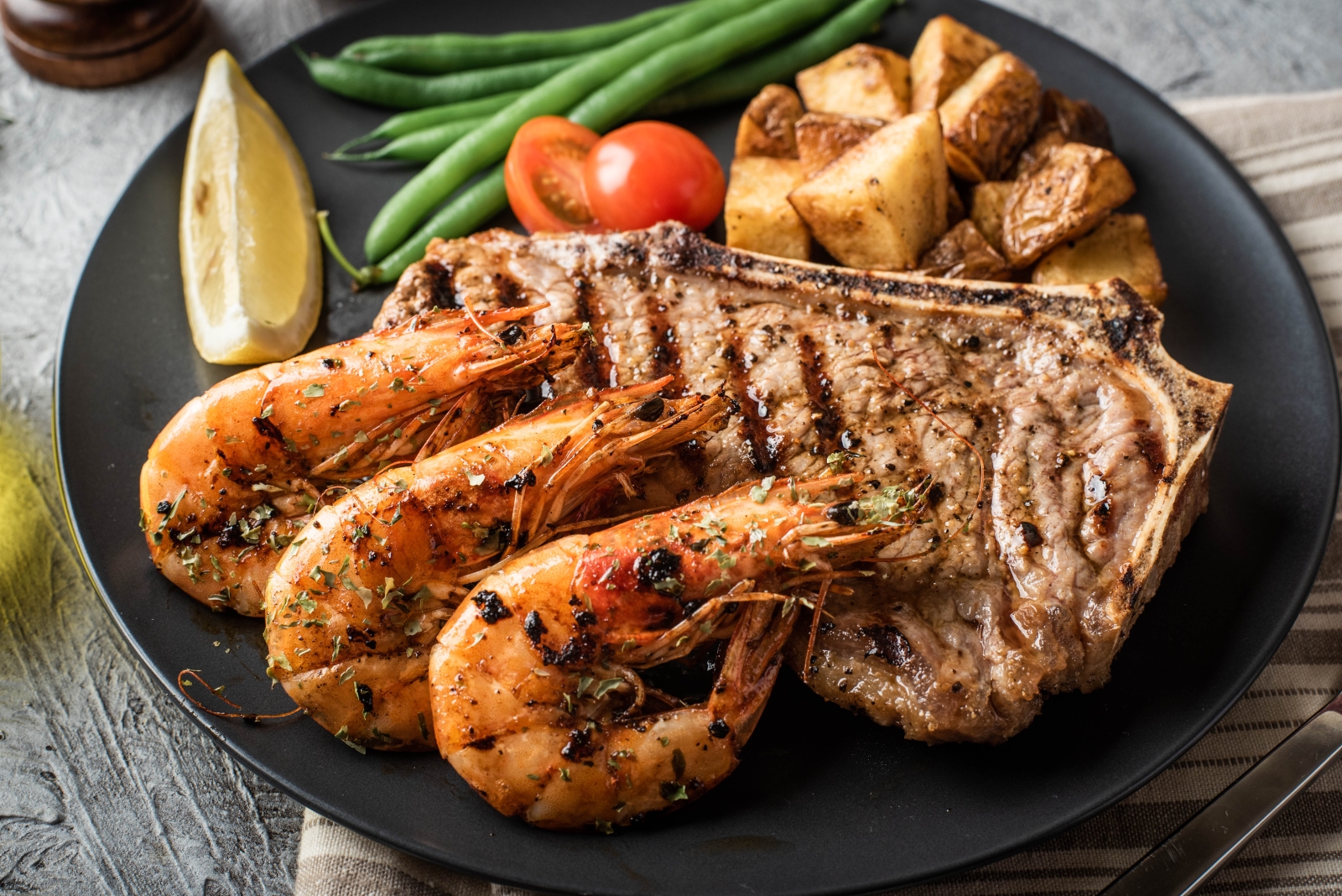 Seafood and steak on a dish with vegetables.