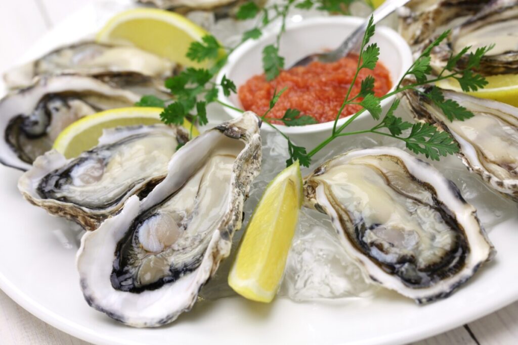 Oysters on a plate with lemon and sauce.