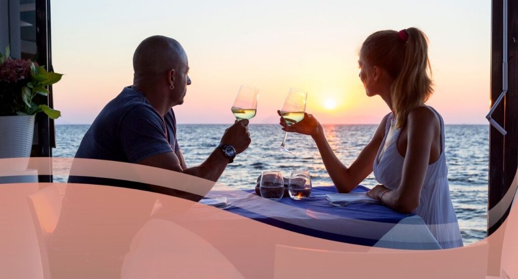 man and woman toast with wine glasses over sunset view